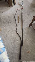 Full view of the three items laid out on carpet: spear, bull whip, and flute.