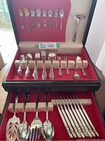 Full view of the open wooden red felt-lined case showing rows of silver plated cutlery including forks, spoons, knives, and serving pieces with souvenir teaspoons in lid.