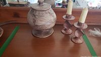 Overall view showing the brown pottery fish jar with lid and two candlesticks with candles.