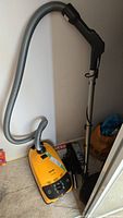 Full view of yellow Miele Solaris canister vacuum with hose and wand
