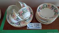 Photo showing four teacups stacked inside four saucers and four luncheon plates with floral gold trim pattern