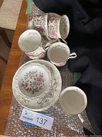 Photo showing several teacups, saucers, side plates arranged on bubble wrap; floral and gold detail visible