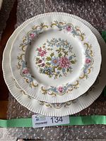 Stack of 2 plates showing the floral design with pink, blue and gold accents and scalloped rim.