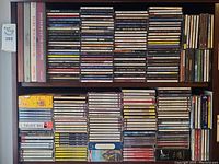 Two shelves filled with assorted audio CDs in jewel cases