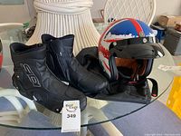 Motorcycle helmet and boots on a glass table, with helmet showing the red, white, and blue color pattern and visor.