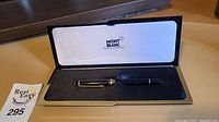 Open Montblanc presentation case showing black resin pen in foam bed and satin-lined lid with Montblanc logo