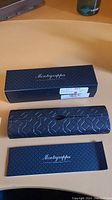 Montegrappa Italia patterned cardboard sleeve alongside hard case and booklet atop desk