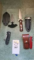 Overview of all knives and multi-tool laid out on carpet, including fixed blade hunting knife, push dagger cutter, folding pocket knife, Swiss Army multi-tool with pouch.
