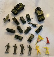 Full lot view showing 16 army toy vehicles and 3 soldiers, including 2 yellow and 1 red plastic figurines and small foam jets