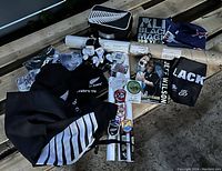 View of the lot showing All Blacks memorabilia including flags, hoodies, scarves, hats, posters, keychains, and figurines arranged on a wooden surface.