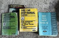 Photo showing four manuals: 1980 Ford Car Shop Manuals (green and yellow), 1969 Ford Truck Shop Manual (blue), and Off Road Handbook (black).