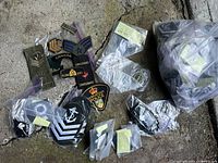 Top view photo of assorted military police and sea cadet patches spread on a stone or concrete surface. Several patches are in small clear plastic bags with labels, others are loose.