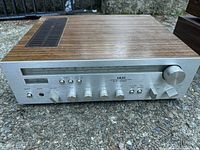 Vintage Akai stereo receiver with wood grain top and front control panel showing various knobs and switches.