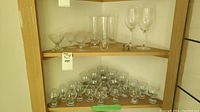Full shelf view showing various crystal and glass stemware including wine glasses, cocktail glasses and tumblers.