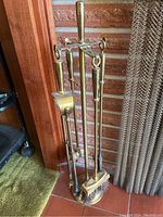 Full view of brass fireplace tool set on stand showing poker, shovel, brush, and tongs