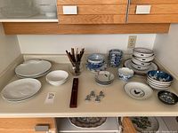 Wide view of counter with plates, bowls, chopsticks, and chopstick rests arranged