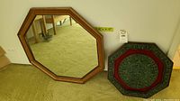 Both items displayed side by side on carpeted floor showing mirror with wooden frame and Aztec calendar plaque.