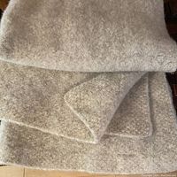 Folded view of the pale grey hand knit merino wool throw displaying its texture and thickness.