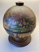 Front view of the vintage old world map printed globe with wooden base and knob.