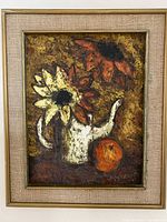 Full view of framed oil painting showing the entire artwork including frame and textured sunflowers inside a watering can with a fruit on the side.