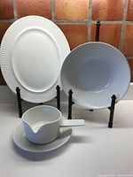 Full lot showing all items: oval platter, large serving bowl, gravy boat with saucer, all white porcelain with ridged linear pattern along edges.