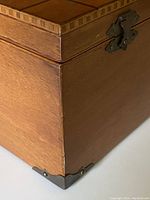 Close-up side view of wooden box showing brass corner protector and original brass hinge