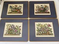 Top view of all four Pimpernel hot plates arranged together showing distinct floral illustrations on blue bordered plates.