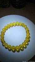 Clear image showing the circular bracelet made of round honey golden translucent amber beads on a light background