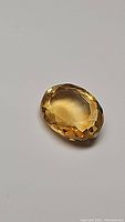 Close-up photo of oval cut golden citrine gemstone showing facets and color