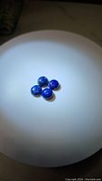 Four natural round cabochon Lapis Lazuli gemstones on a white background, showing shape, size and color.