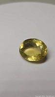 Oval faceted lemon yellow citrine gemstone on white background