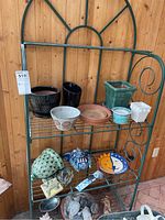 Green metal bakers rack with four shelves against a wooden background, showing general condition and details.