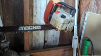 Echo 300t gasoline chainsaw with bar and chain mounted on wall showing used condition.