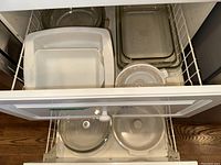 Top drawer view of stacked white ceramic and clear glass Pyrex baking dishes and mixing bowls.