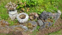 Overview of all four garden decor items arranged on mossy stones in a garden bed
