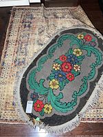Four mats stacked, top mat oval with floral design and fringe, beneath a traditional oriental patterned mat.