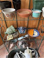 Photo showing decorative ceramic wall accents including sun and moon plate, blue face mask, ceramic turtle figurine, small tile, and landscaping stones