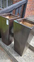 Two tall dark brown ceramic planters side by side, showing height and shape.