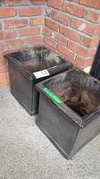 Two ceramic planters side by side showing square shape and dark glaze with weathered interior.