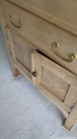 Close-up of the side table front showing drawer with brass handle and two cabinet doors with knob, side panel detail.