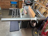 Craftsman 10-inch contractor table saw on wheeled cart with extension wing to the left and fence system with wooden auxiliary fence.