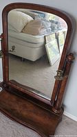 Front view of vintage wooden mirror with reflection visible and candlesticks attached on sides.