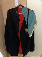 Full view of vintage black nurse cape with blue hood and red lining.