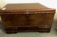 Closed vintage wood cedar storage chest showing wood grain and carved base details