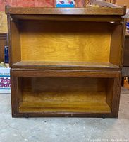 Front view of two stacked barrister book case sections with open fronts, showing the wood grain and open empty interior compartments.