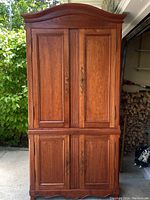 Full view of the tall wooden cabinet with upper and lower double doors showing overall design and finish.