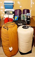Photo of all camping items on a table showing sleeping bags, coolers, carry case, and other gear.
