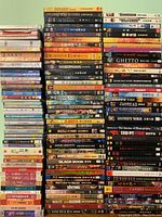 Photo showing multiple stacks of DVD and CD cases arranged vertically featuring a range of titles in English and Asian languages.