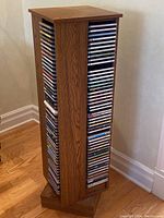 Wooden rotating CD rack filled with multiple CDs on all visible sides displaying their spines.