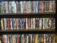 Photo showing three shelves filled with DVDs and Blu-Rays arranged by title spine, featuring various genres.
